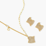 Gold-plated wavy jewelry set with crystal detailing featuring necklace with dual chains and matching textured earrings