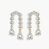 Gold-plated earrings with vertical line of clear crystals and teardrop pendants on neutral background