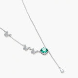 Sterling silver necklace with butterfly charms, green moissanite center stone, and teardrop crystal pendant on white background.