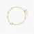 Delicate gold chain bracelet with baroque pearl centerpiece and small freshwater pearls on cream background.