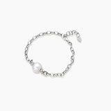 Rhodium-plated silver chain bracelet with single white freshwater pearl and heart charm clasp on cream background