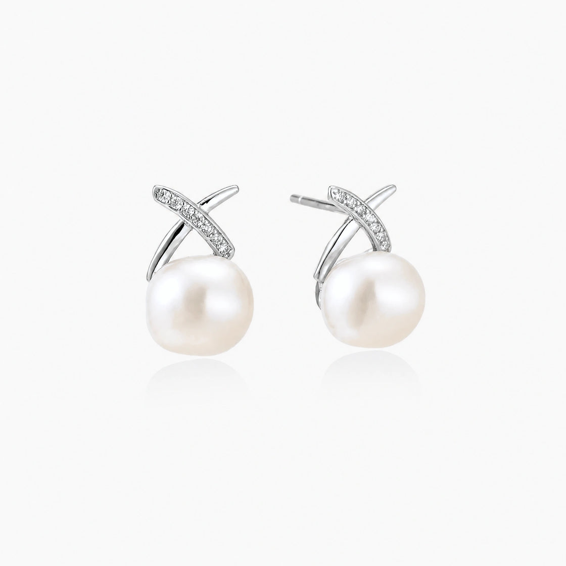 Rhodium-plated silver stud earrings with sparkling X design above lustrous round freshwater pearls on white background.