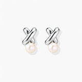 Rhodium-plated silver earrings with twisted X design and freshwater pearl drops on beige background