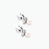 Rhodium-plated silver earrings with twisted X design and freshwater pearl drops on beige background