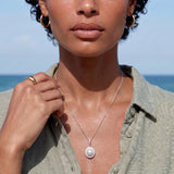 Oval sterling silver pendant with crystal halo surrounding a white freshwater pearl on delicate chain