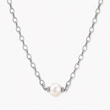 Dainty rhodium-plated silver chain necklace with centered 10mm freshwater pearl and crystal accents on cream background