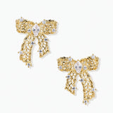 Gold-plated bow earrings with openwork design, marquise center stones, and flowing ribbon tails adorned with zirconia crystals.
