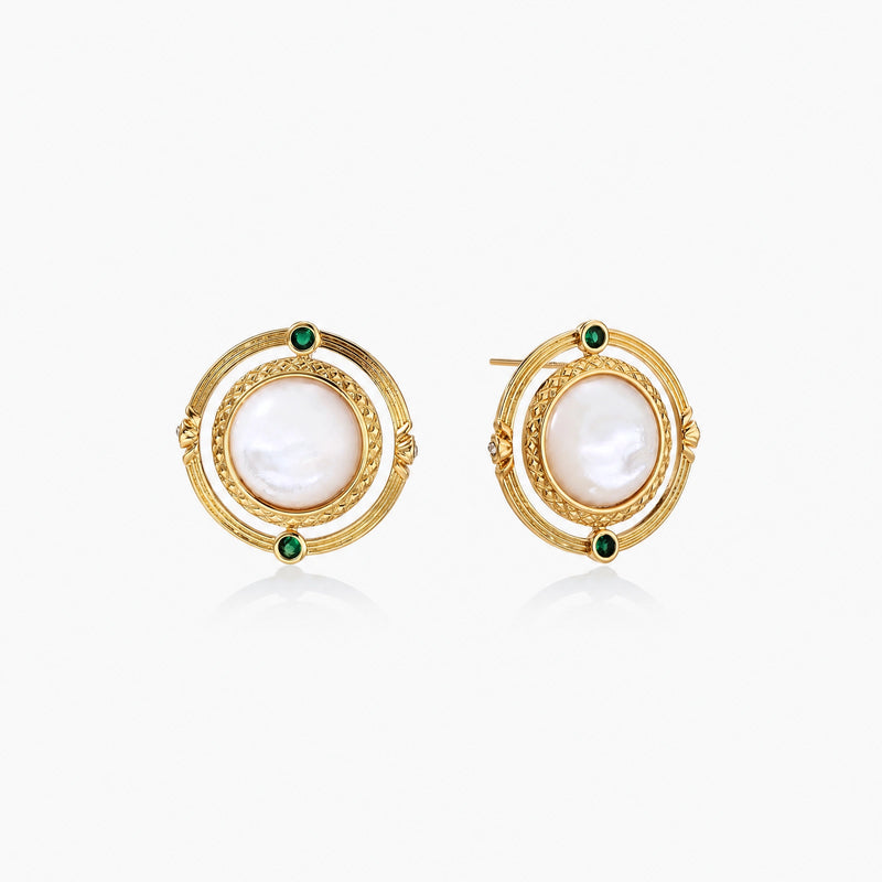 Circular gold stud earrings with iridescent mother-of-pearl center and green zirconia accents on cream background.