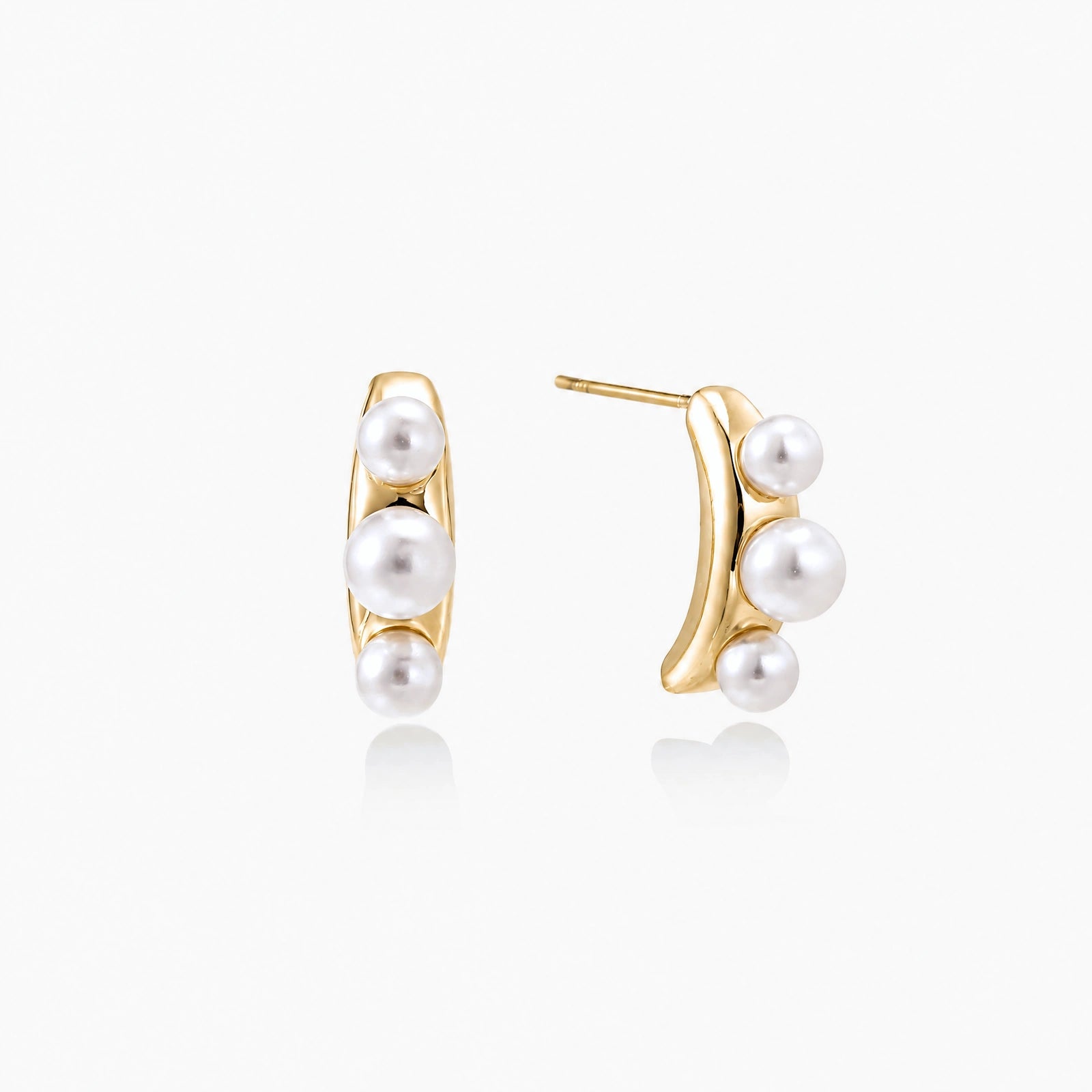 14K gold-plated curved stud earrings with three white freshwater pearls aligned vertically on cream background