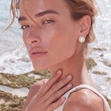 Round 14K gold-plated stud earrings with a mother of pearl center surrounded by baguette-cut crystals, 16mm.