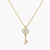 Delicate gold key pendant with heart-shaped bow and crystal pavé detailing on fine chain against cream background.