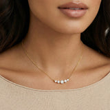 Delicate 14K gold-plated necklace with five graduated zirconia stones arranged in a curved arc on fine chain