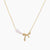 Delicate gold necklace with three white pearls and crystal-embellished bow pendant on cream background