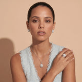 Silver ring with lustrous white pearl center surrounded by sparkling crystal halo on light background.