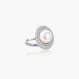 Silver ring with lustrous white pearl center surrounded by sparkling crystal halo on light background.