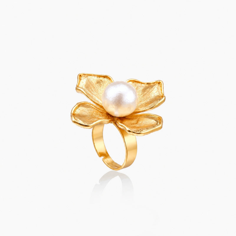 Gold-plated flower ring with textured petals and white cotton pearl center on cream background