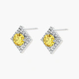 Close-up of diamond-shaped stud earrings with yellow moissanite centers and clear stone halos in sterling silver setting