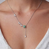 Sterling silver necklace with butterfly charms, green moissanite center stone, and teardrop crystal pendant on white background.