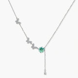 Sterling silver necklace with butterfly charms, green moissanite center stone, and teardrop crystal pendant on white background.