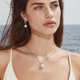 Platinum-plated sterling silver necklace with round clear crystal pendant and decorative bail on neutral background.