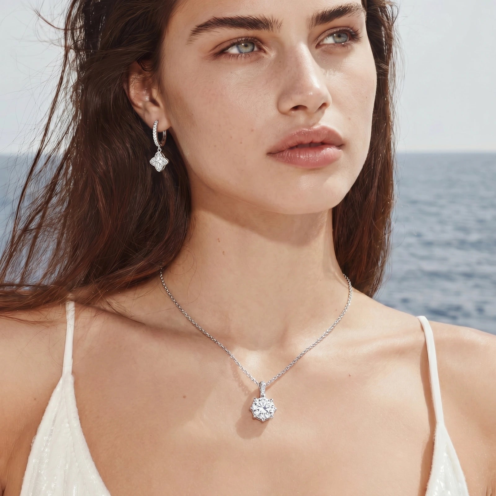 Platinum-plated sterling silver necklace with round clear crystal pendant and decorative bail on neutral background.