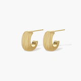 Small gold huggie earrings with matte finish, 14mm diameter, shown against cream background for everyday elegance.