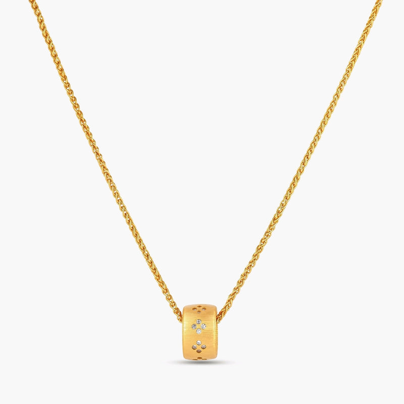 Gold-plated cylindrical ring pendant with brushed finish and scattered crystal accents on a wheat-link chain, cream background.