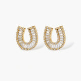 Gold-plated horseshoe necklace and earring set with baguette and round crystals arranged in geometric pattern on white background.