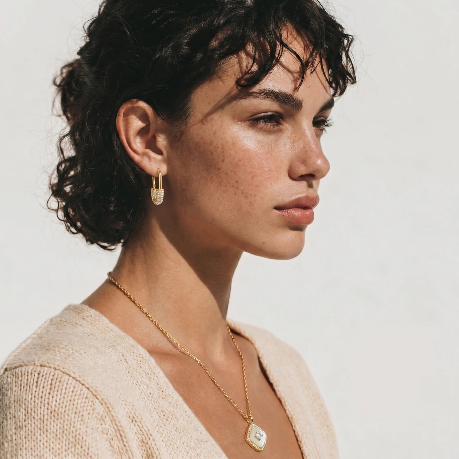 Gold-plated huggie hoop earrings with pavé zirconia stones covering the bottom curve, shown in open and closed positions.