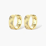 Gold-plated hoop earrings with textured surface and raised floral motifs set with clear zirconia stones on cream background.
