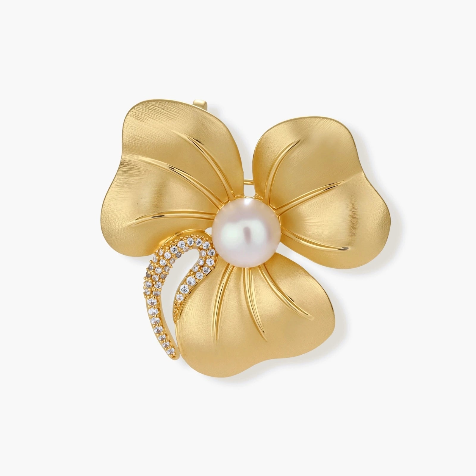 Gold-tone three-petal flower brooch with a brushed finish, round white bead center and zirconia crescent on a cream background.
