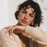 Gold-plated hoop earrings fully covered in sparkling zircon crystals with hinged closure on neutral background