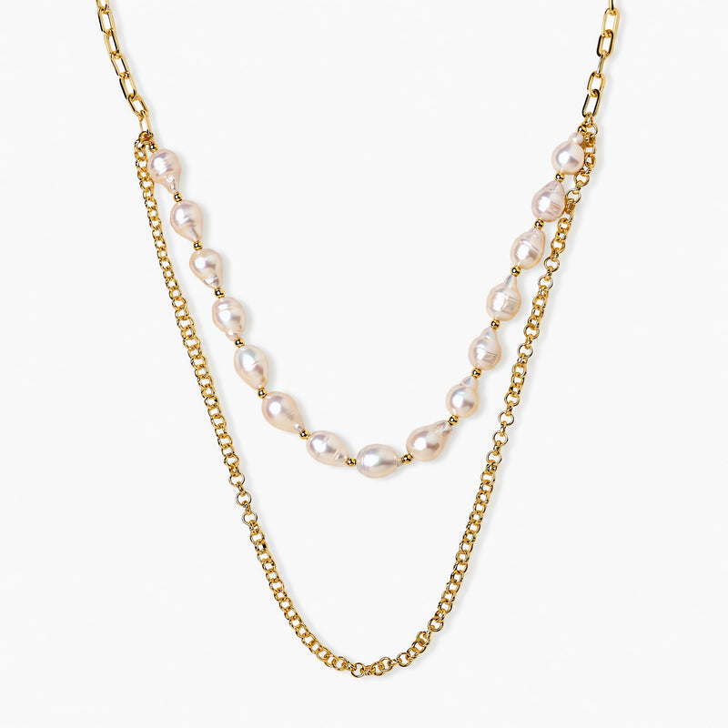 Layered gold chain necklace with organic baroque freshwater pearls and adjustable length on cream background