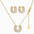 Gold-plated horseshoe necklace and earring set with baguette and round crystals arranged in geometric pattern on white background.