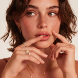 Close-up of adjustable gold-plated ring with continuous row of round zirconia stones on neutral background.